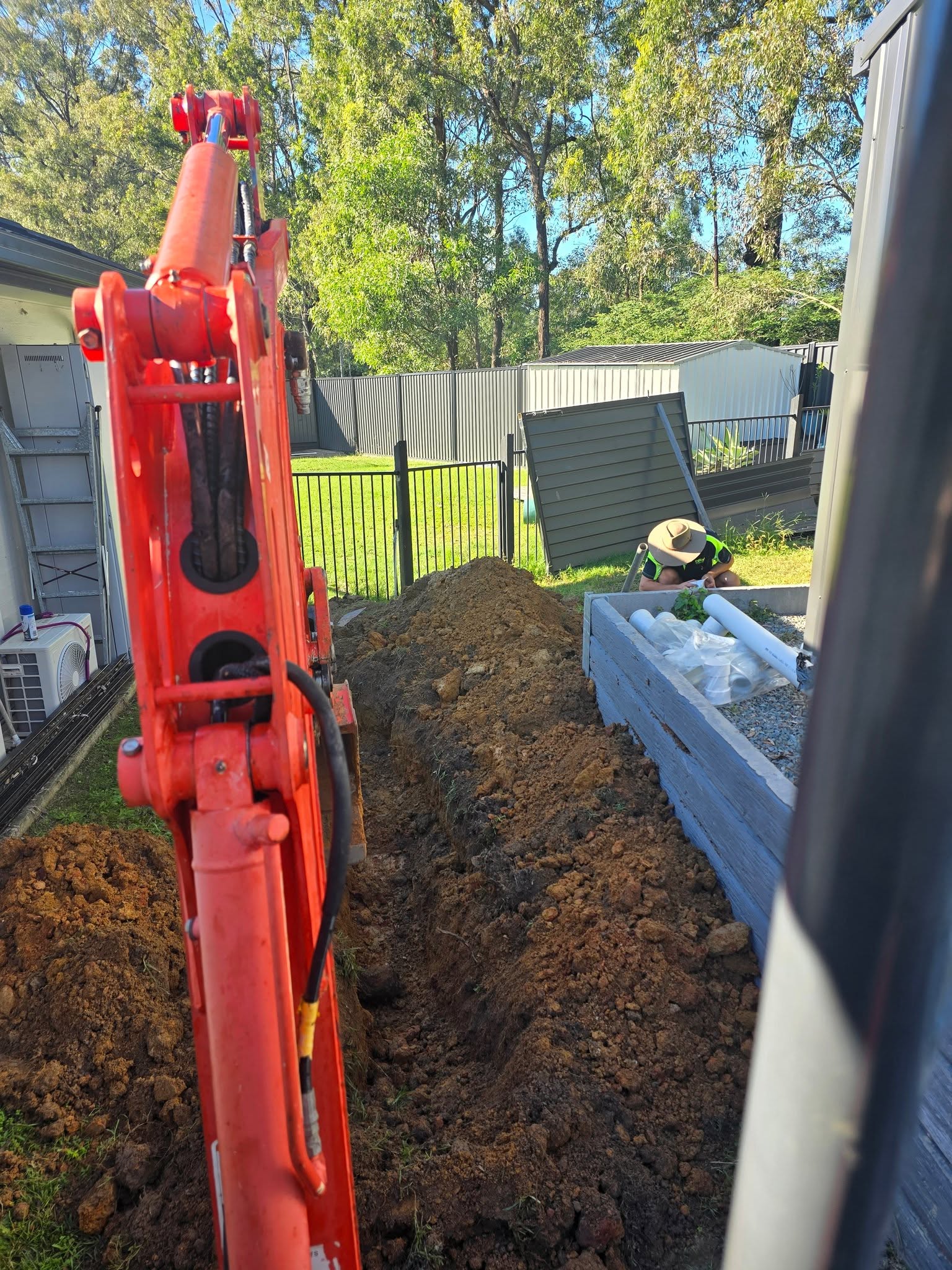 Mini excavator boom over a backyard trench